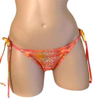 Low waist tie side ruched back bikini bottoms in orange holographic floral print with beads at strap ends front view