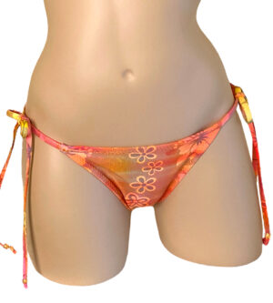Low waist tie side ruched back bikini bottoms in orange holographic floral print with beads at strap ends front view